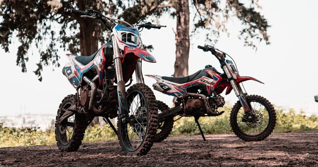 Alt two different pit bikes for youth riders parking on the trail road.