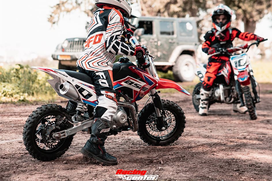 Two kid dirt bike riders riding dirt bike with full body riding equipment and gears